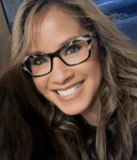 Woman wearing glasses smiling.