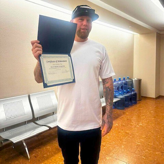 Man in a white shirt holding certificate for photo.