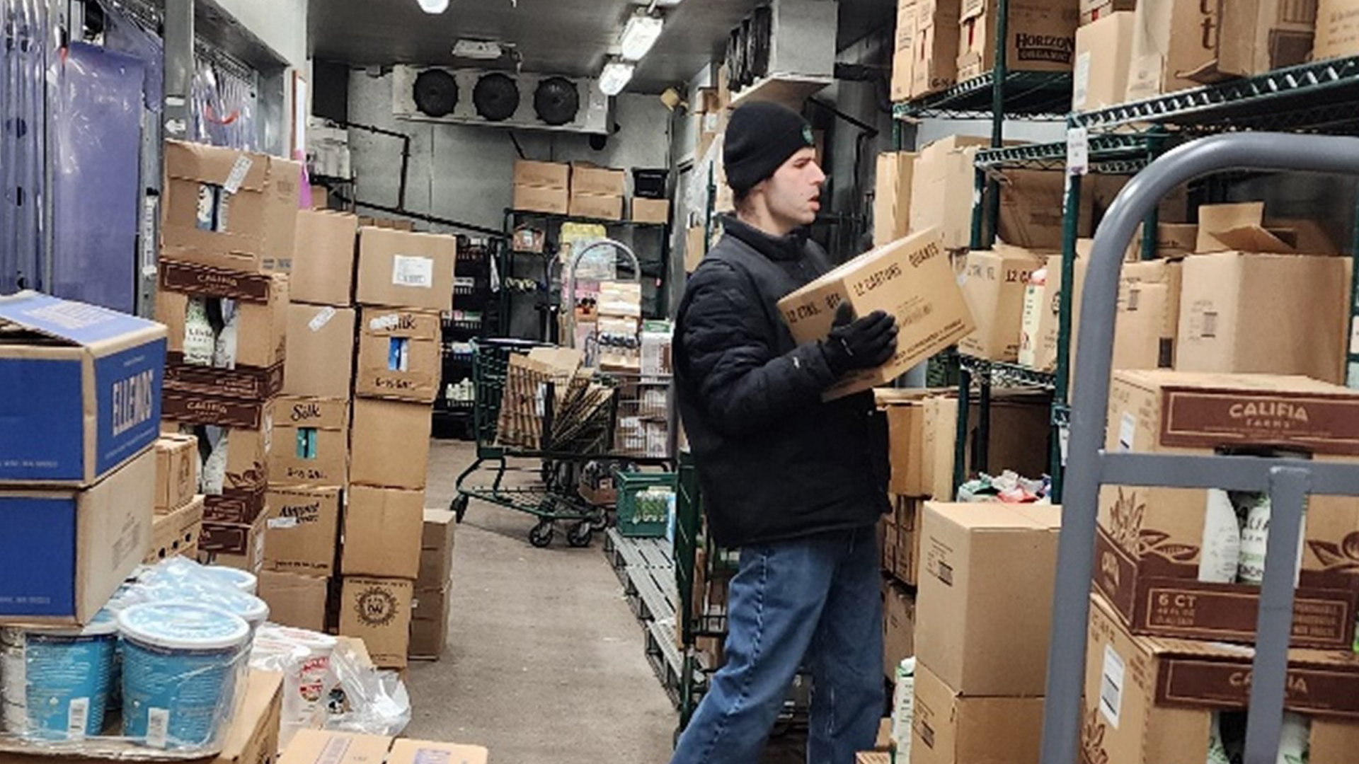 Young man carrying boxes to a shelf.